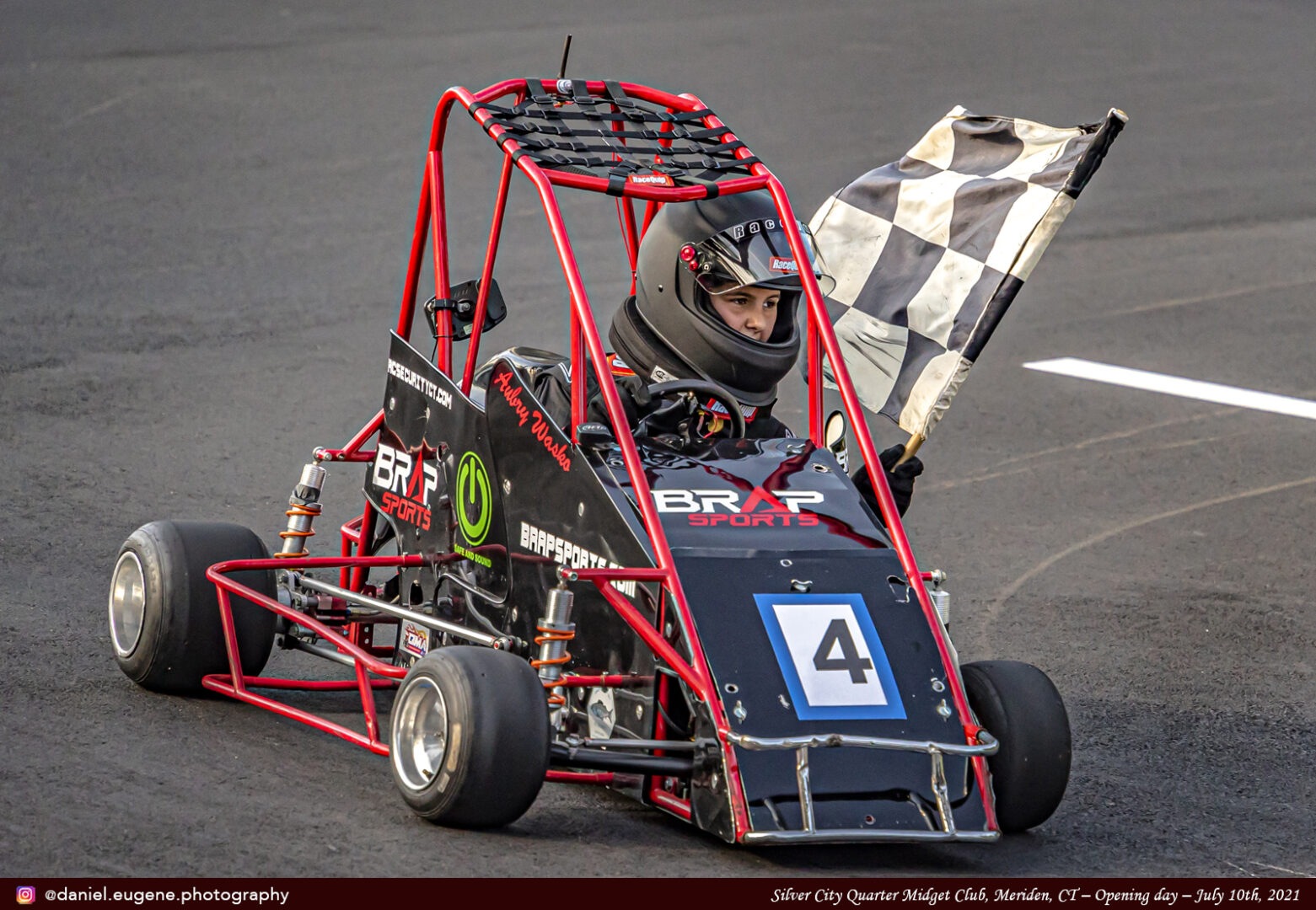 A Boy Holding a Finish Flag While Driving a kart